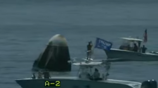 Private craft with Trump sign passes in front of Space X Capsule