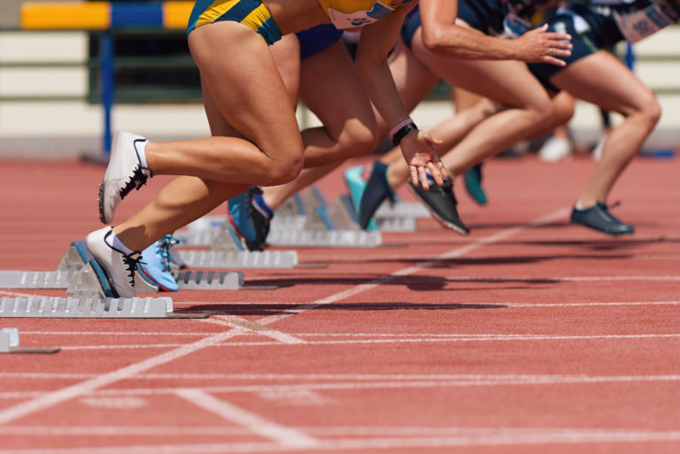 Group of female track athletes on starting blocks
