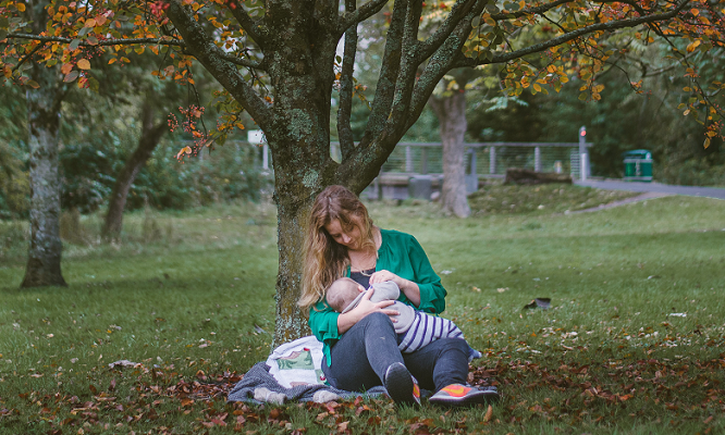 mother breatfeeding out doors park tree