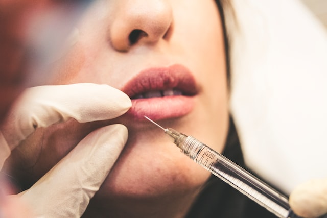 Lip woman needle botox injection Photo by Sam Moghadam Khamseh on Unsplash