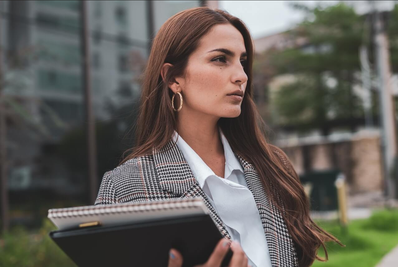 brunette woman with note books in business attire