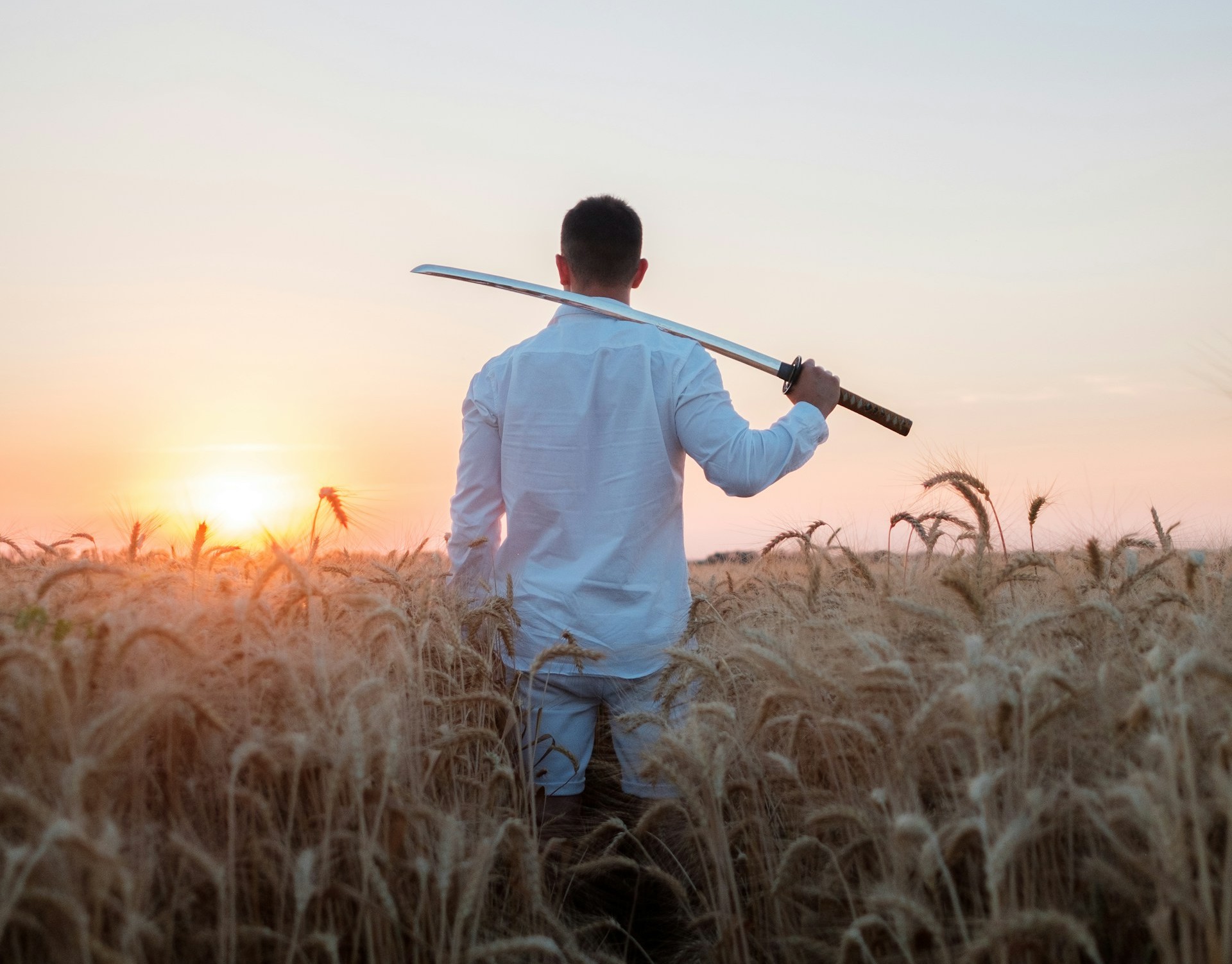 a man with samuri sowrd, katana in a field
