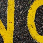 the word no in yellow paint on asphalt